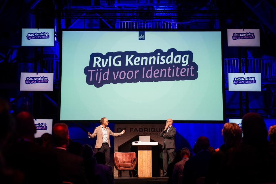 Kennisdag presentatiescherm met logo en twee sprekers